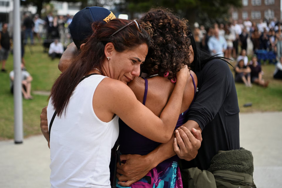 Orang-orang berpelukan saat mengunjungi tugu peringatan sementara setelah serangan terhadap perayaan hari raya Yahudi di Pantai Bondi, Sydney, Australia, 15 Desember 2025